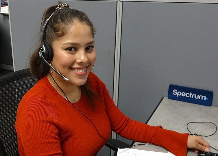 A female Spectrum Call Center Representative in a red sweater wearing a telephone headset